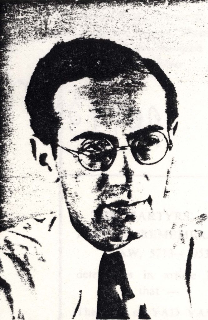 A man with glasses and a tie poses for a photograph. The photograph itself is old, and somewhat washed out. 