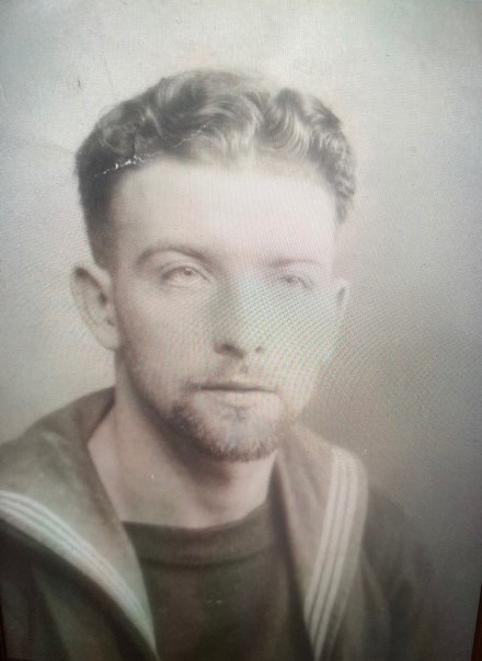 A man in a sailor's uniform sits posing for a portrait.